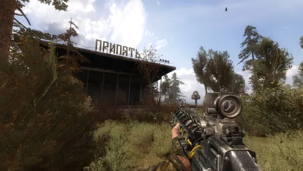 A first-person perspective of a player holding a detailed and realistic assault rifle with a scope, aiming at an abandoned building in a forested area. The environment is lush with greenery, including trees and bushes, under a partly cloudy sky. The building has Cyrillic text on it, suggesting a Russian or Eastern European setting. The overall scene conveys a sense of tension and immersion typical of a modern military shooter game.